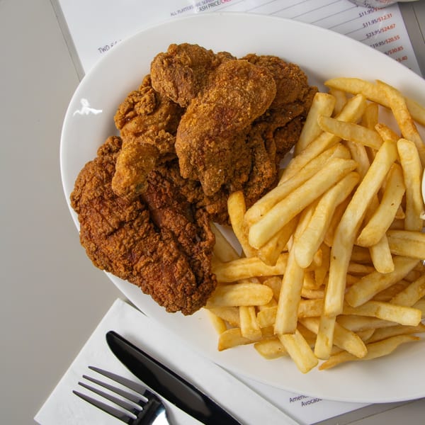 Seaport Diner's crispy fried chicken and golden french fries on a white plate, with a menu in the background.