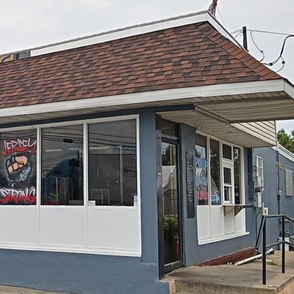 Exterior of Seaport Diner, a blue building with a brown shingled roof and large windows.
