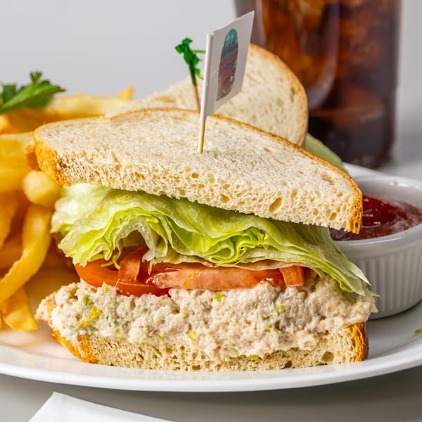 Seaport Diner's tuna sandwich with lettuce, tomato, fries, ketchup, and a drink.