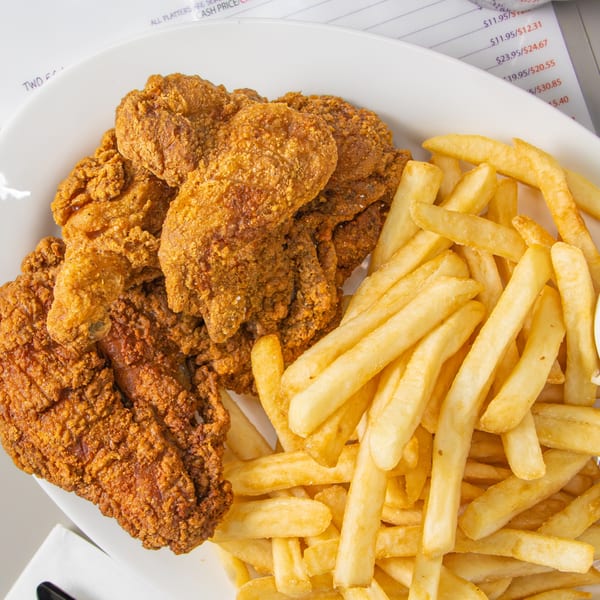 A white plate of crispy fried chicken and golden french fries from Seaport Diner.